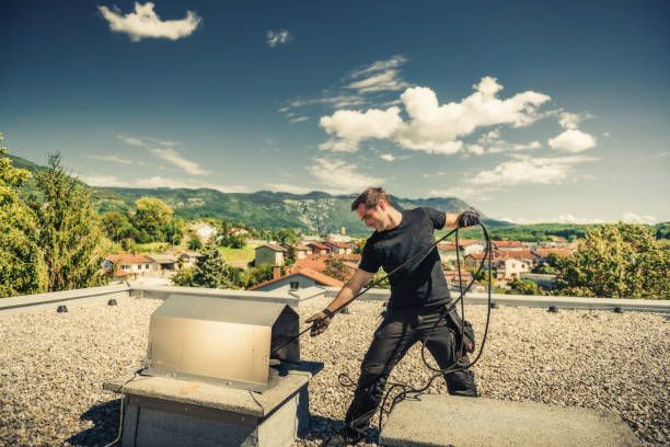 Technician servicing a metal flue on a flat roof